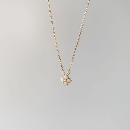 Detailed view of the gold-plated clover pendant with shimmering opal stones.