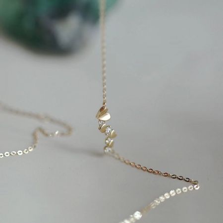 Vista completa del collar de zircon irregular en forma de corazón contra un fondo neutro.