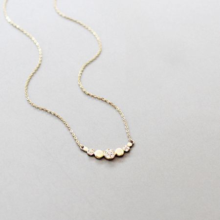 Close-up of the pendant with alternating gold balls and clear gemstones.