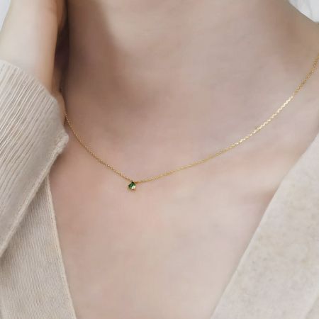 A clear view of the small, elegant green emerald gemstone on the necklace.
