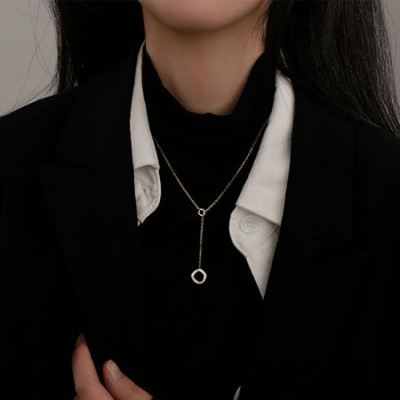 Primer plano de una mujer usando el collar con colgante hexagonal de oro.