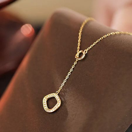Collar geométrico de oro sobre un fondo blanco.