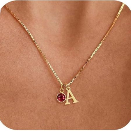 Close-up of the 'A' initial necklace with a striking red birthstone.