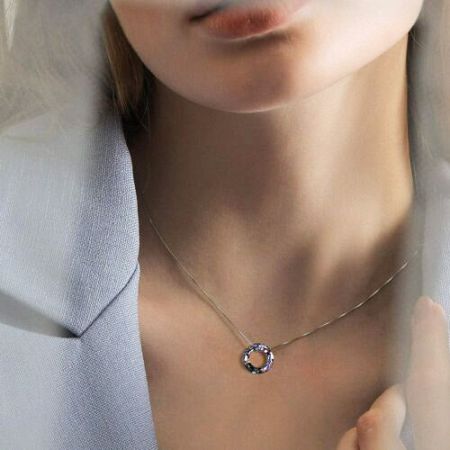 Una collana sorprendente in tono oro con un pendente a cerchio di pietre preziose multicolori.