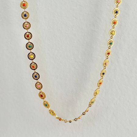 Gros plan sur les maillons complexes et les pierres précieuses colorées d'une chaîne de taille en émail en forme de disque solaire.