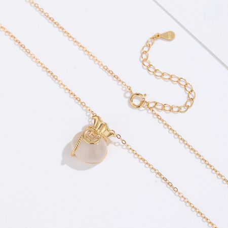 Un collar de oro de la colección con un gran colgante de piedra redonda y pálida, destacando su elegante simplicidad.