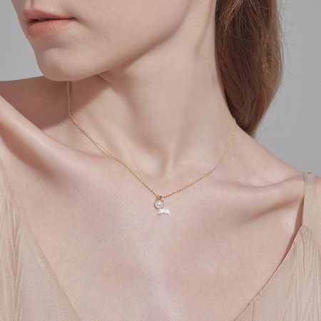 Modello che indossa l'elegante collana d'oro con pendente a perla e ala.