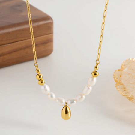Conjunto de collar choker de perla de agua dulce barroca en acero inoxidable. - Una toma de estudio detallada del collar de cadena tipo clip de papel de acero inoxidable, destacando la perla de agua dulce barroca natural y el elegante colgante en tono dorado.