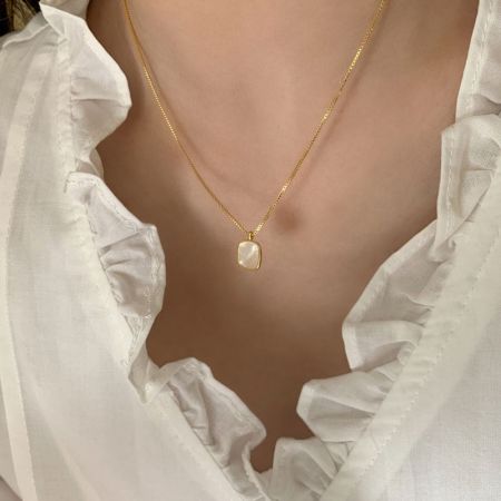 Vista detallada del collar con colgante de concha en oro rosa, destacando la cadena y el cierre.