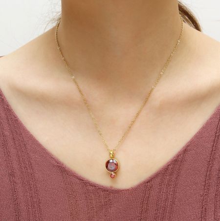 Primo piano della collana placcata in oro con un pendente in zirconia cubica rosso fuoco.