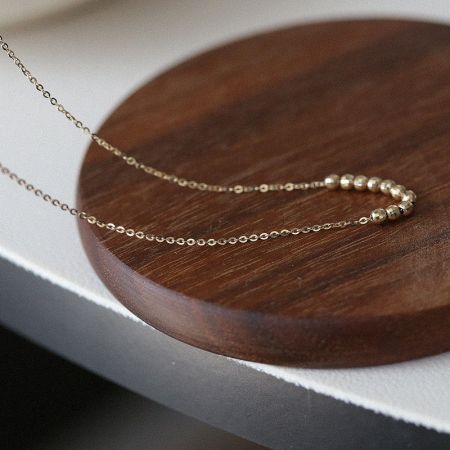 Collar de Cuentas Facetadas en Plata Esterlina 925 Bañada en Oro de 18K al por mayor - Una disposición plana del Collar de Cuentas Facetadas en plata esterlina 925 bañada en oro de 18K, exhibido en una plataforma de madera para resaltar su calidad y diseño.