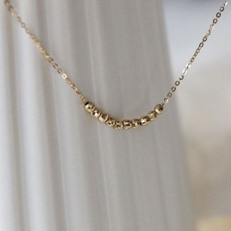 Détail en gros plan des perles facettées en or 18K sur le collier en argent sterling.