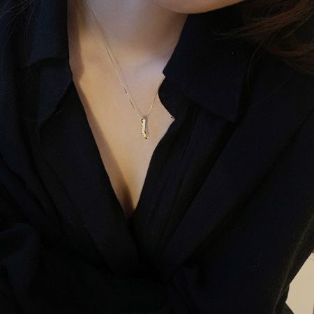 Detailed shot of the gold interlocking cross and rectangle pendant necklace.