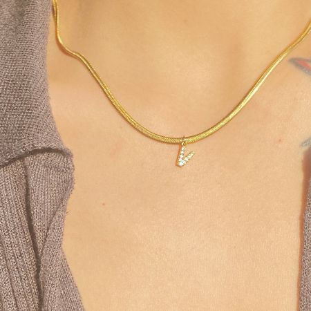 Een close-up van de 'V' initialenhanger ketting, die de briljante glans en kwaliteit van het vakmanschap benadrukt.