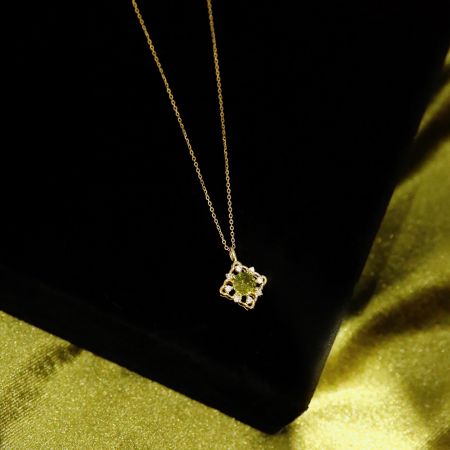 Detailed view of the flower-shaped green zircon pendant on the 14K gold plated necklace.