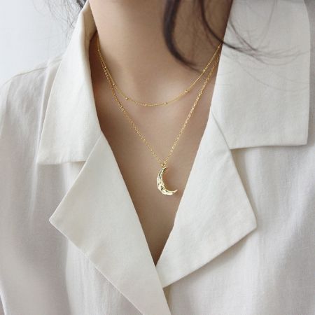 Un look élégant avec le collier pendentif en croissant doré, parfait pour le superposition.