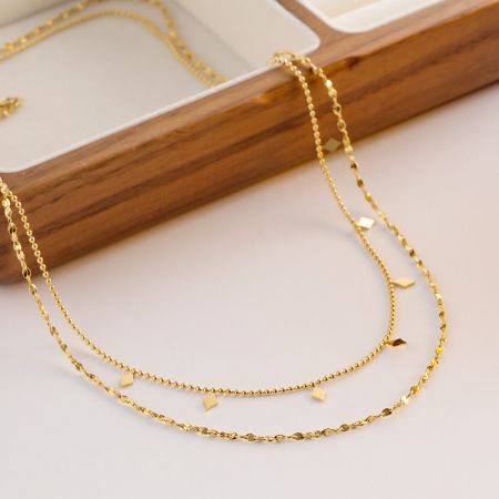 Nahaufnahme der goldenen, geschichteten Halskette mit zarten Würfel-Charms.