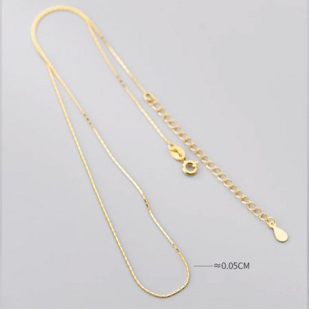 Gros plan sur le collier en chaîne serpent en or, illustrant son design super fin et flexible.