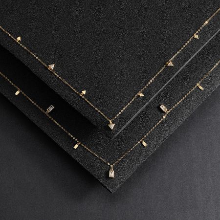 Un paio di collane in argento sterling placcato oro con charm geometrici esposti affiancati.