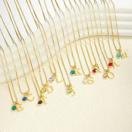 قلائد الأزياء - مجموعة نابضة من قلائد الأزياء الذهبية من JR Fashion Accessories، تتميز بمعلقات حروف متنوعة وأحجار كريمة ملونة.