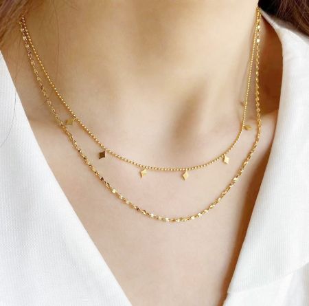 Set van 5 Roestvrijstalen Gouden Dubbele Gelaagde Kettingfranje Kettingen - Een vrouw die de elegante roestvrijstalen gouden dubbele gelaagde kettingfranje kettingen draagt, die hun stijlvolle uitstraling toont.