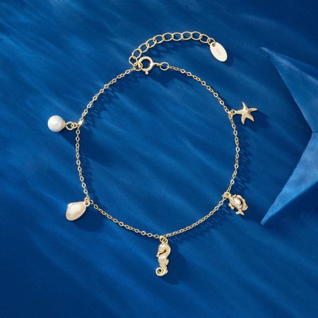 海馬、ヒトデ、貝殻のチャームを展示した金色のオーシャンチャームブレスレットの詳細ビュー。