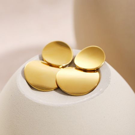 Gedetailleerd uitzicht op de gelamineerde schijf oorbellen die de textuur en gouden afwerking tonen.