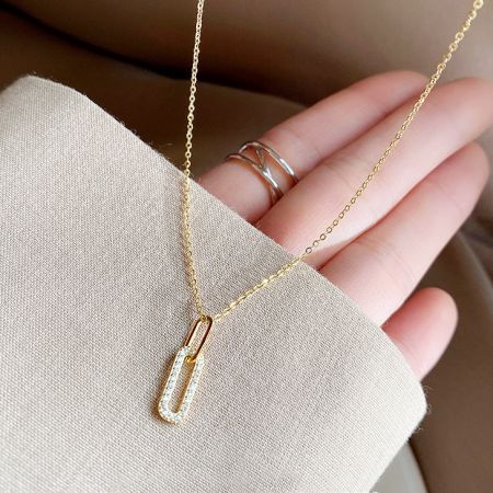Close-up of the sparkling pavé CZ zircon oval pendant on the gold necklace chain.