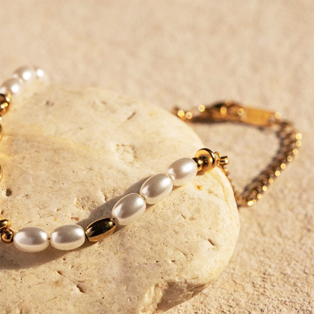 Das goldfarbene Perlenarmbandset, das auf einem Naturstein präsentiert wird, für einen eleganten Look.