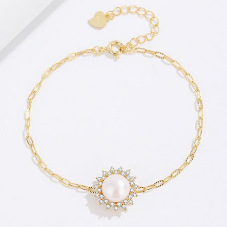 Close-up of the gold bracelet with a brilliant pearl and diamond-like zircon pendant.