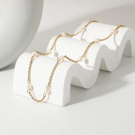 Matchande guldkedjearmband med pärldetaljer.