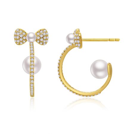 Vista detallada de los pendientes de perlas dobles con gancho de oro que muestran el intrincado diseño de lazo con acentos de perlas y diamantes.