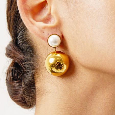 Vista en primer plano de una mujer que lleva los pendientes de cúpula hemisférica de oro y perlas.