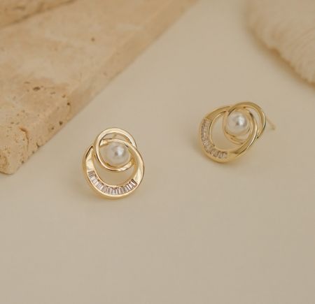 Vue latérale des boucles d'oreilles à clou en perles à double anneau, mettant en valeur le design en tourbillon et la brillance de la perle.