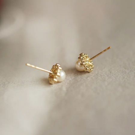 A pair of simple yet elegant gold pearl stud earrings from the set.