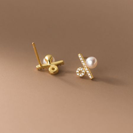 Elegant gold pearl earrings with decorative stone elements, displayed on a white surface.