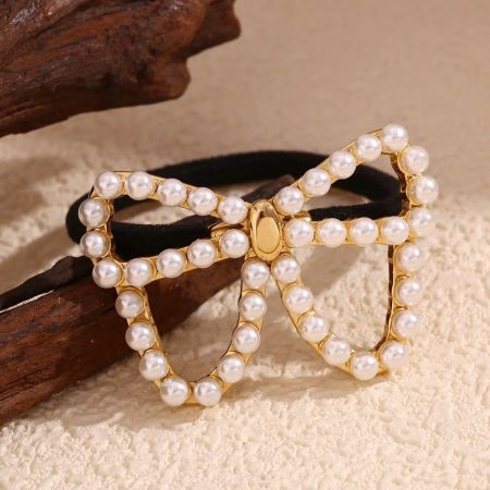 Detailed view of the gold butterfly charm with pearl embellishments.