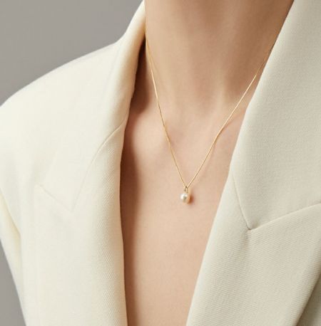 Close-up view of the minimalist gold-plated pearl necklace, highlighting the luster of the freshwater pearl.