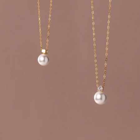 Comparison shot of two gold pearl necklaces showcasing the fine details of the pendant.