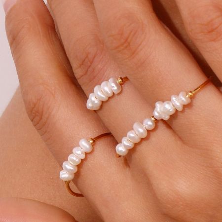 A model's hand displaying two gold rings from the baroque freshwater pearl set, demonstrating how they can be stacked or worn separately.