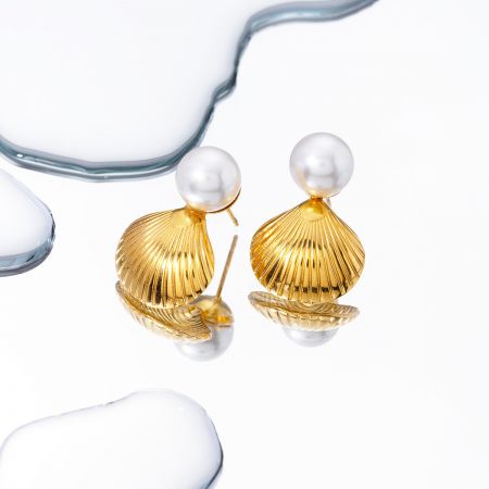 Exhibición elegante de los aretes de concha de oro con perlas.