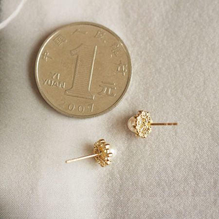 Size comparison of the gold pearl stud earrings next to a coin.