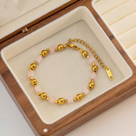 木製のジュエリーボックスに優雅に展示されたステンレススチールのピンクの天然石ブレスレット。