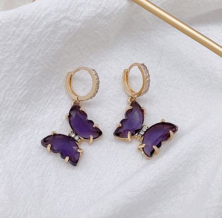 Un autre angle des boucles d'oreilles huggie en papillon violet, montrant la fermeture à tige et l'artisanat complexe.