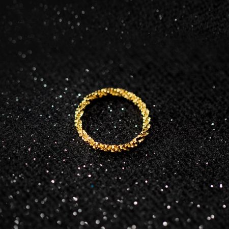 A close-up of a gold bling ring from the set on a black glitter background.