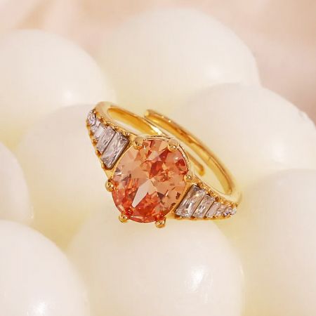 Anello regolabile in oro champagne con una prominente pietra ovale arancione e accenti di diamante bianco.