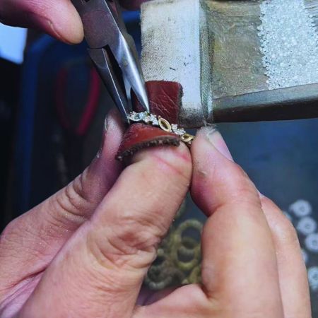 Un artesano trabajando cuidadosamente en un anillo de diamante de oro personalizado.