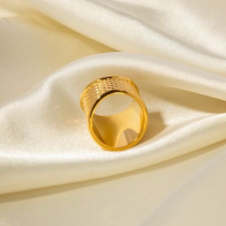 Elegant guldtexturerad ring visad på en lyxig krämfärgad satinbakgrund.