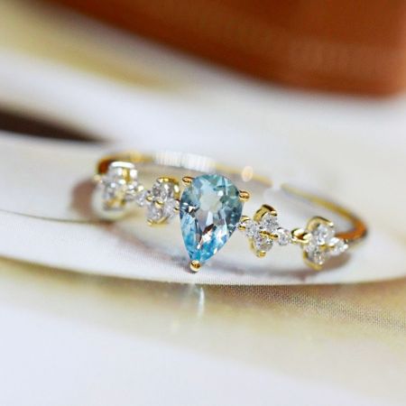 Anello a forma di pera in acquamarina in argento sterling 925 (Set di 5) - Un primo piano dell'anello a forma di pera in acquamarina in argento sterling 925, che mostra la pietra centrale in acquamarina a taglio pera circondata da delicate pietre accentuate.