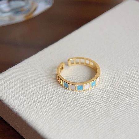 Another ring from the set with intricate blue and white inlays on a gold-plated band.